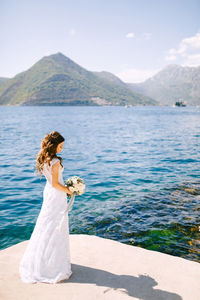 Full length of bride standing against lake