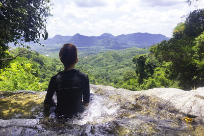 Rear view of man looking at mountains against sky