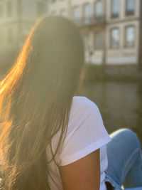 Woman sitting against building