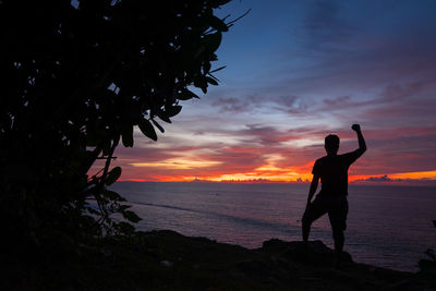 Silhouette man standing at beach during sunset