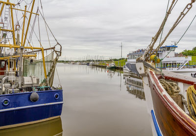 Boats moored at harbor against sky in city