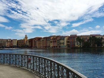 Buildings by river against cloudy sky