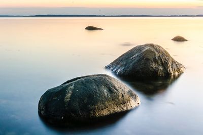 Rocks on sea shore against sky during sunset