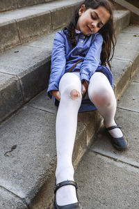 Girl with wounded leg sitting on steps