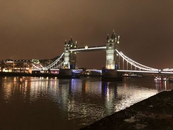 Illuminated suspension bridge over river at night