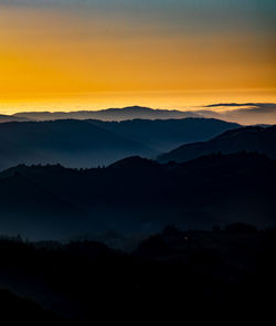 Scenic view of silhouette mountains against orange sky