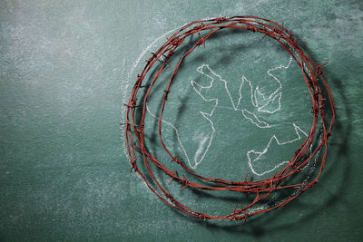 High angle view of rusty barbed wire with globe drawing on blackboard