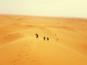 High angle view of people walking at desert against sky