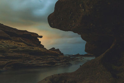 Rock formation on beach against sky