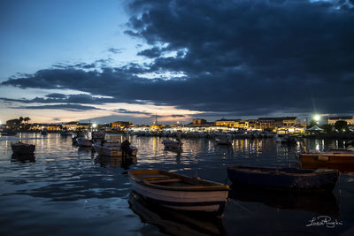 Boats moored in harbor at dusk