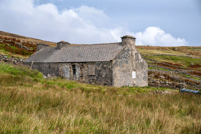 Old house on field against sky