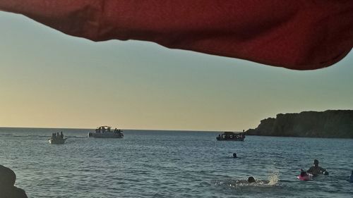 Silhouette man in sea against sky during sunset