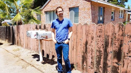 Full length portrait of man standing against building