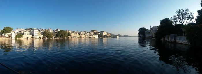 Scenic view of lake by town against clear blue sky