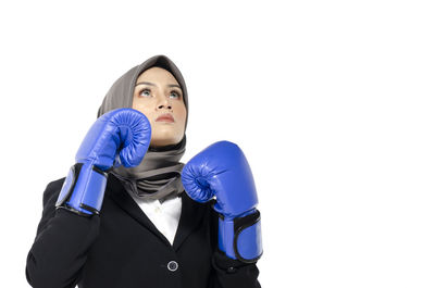 Portrait of young woman standing against white background