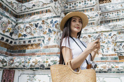 Portrait of beautiful young woman standing against wall