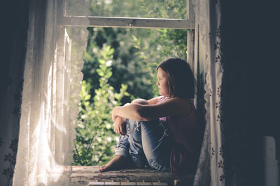 Child girl on the window, the concept of sadness and loneliness, the problems of childhood
