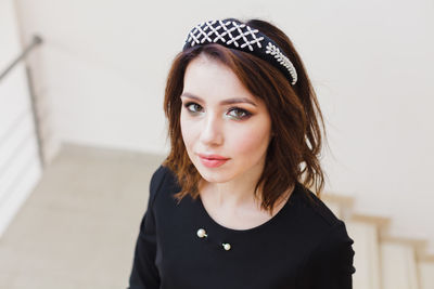 Portrait of young woman standing against white wall