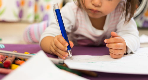 Midsection of girl drawing on paper 