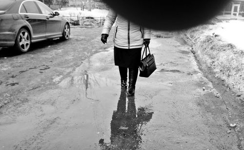 Rear view of man walking on wet road