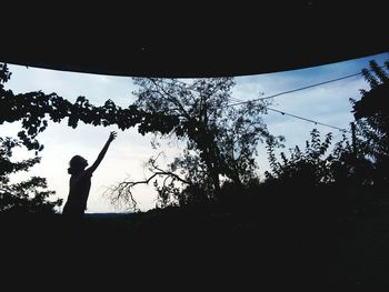 Low angle view of silhouette people standing against sky