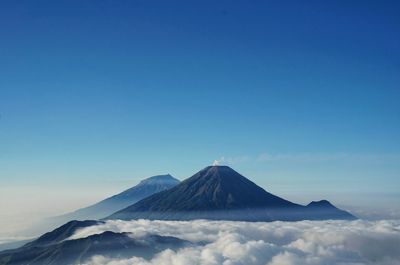 Scenic view of  sindoro and sumbing mountain against clouds and clear blue sky