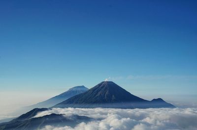 Scenic view of  sindoro and sumbing mountain against clouds and clear blue sky