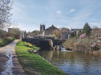 Bridge over river by buildings against sky