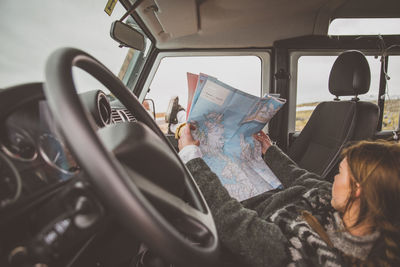 Woman holding map lying down in car