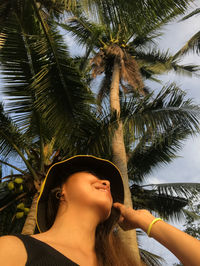 Low angle view of woman looking at palm tree