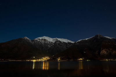 Scenic view of lake by mountains against clear sky at night