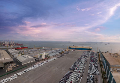 Aerial logistics commercial vehicles waiting to be load on to a car carrier ship at dockyard