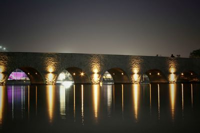 Illuminated bridge against clear sky at night