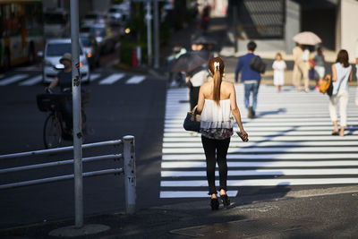 Rear view of woman walking on road in city