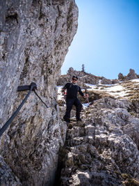 Low angle view of man on rock against sky