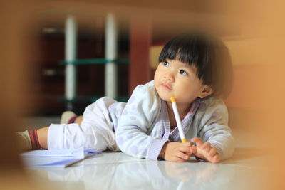 Portrait of cute baby girl sitting on table at home