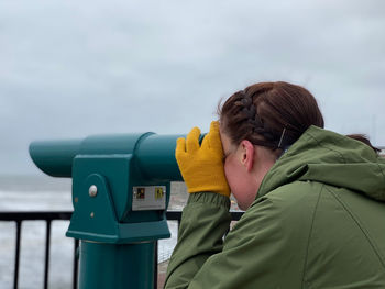 Portrait of woman looking through a telescope at the beach