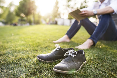 Unrecognizable businessman in the city park sitting on grass reading book