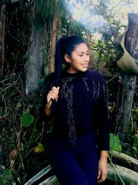 Young woman smiling while sitting in forest