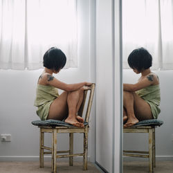 Rear view of woman sitting on chair at home