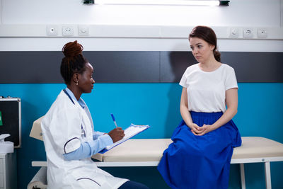 Portrait of female doctor using mobile phone while standing in clinic