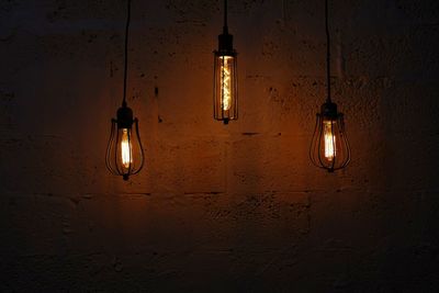 Low angle view of illuminated light bulb hanging on wall