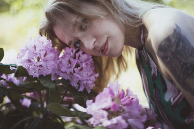 Close up woman bending head over pink flowering shrub portrait picture