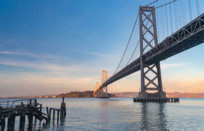 Suspension bridge over sea against sky