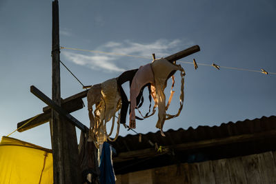 Low angle view of clothes hanging on roof against sky