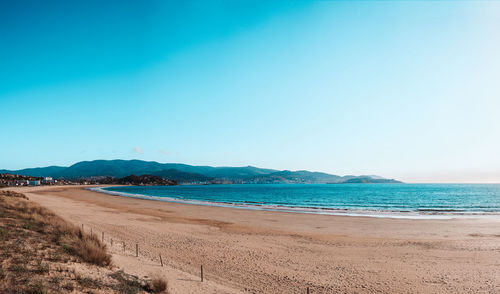 Scenic view of beach against clear blue sky