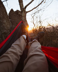 Low section of man relaxing on hammock at sunset