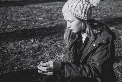 Woman looking away while sitting on field