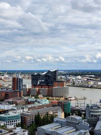 High angle view of city buildings against cloudy sky