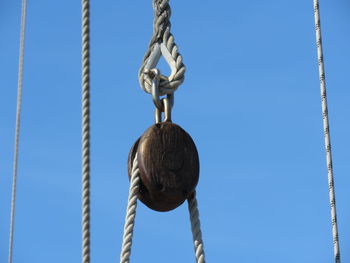 Low angle view of rope with pulley against clear blue sky